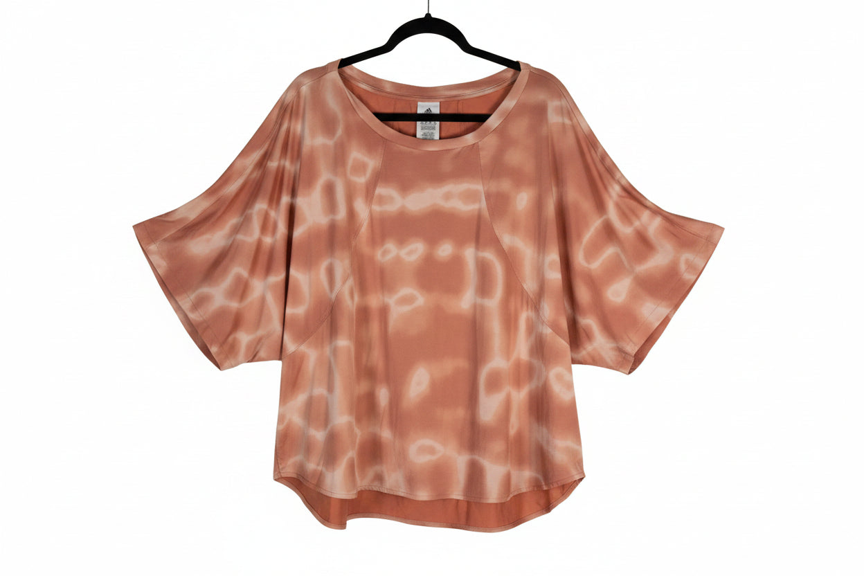 Adidas 11 HONORE' 2X loose, short-sleeve top in a peachy orange color with a white tie-dye pattern.