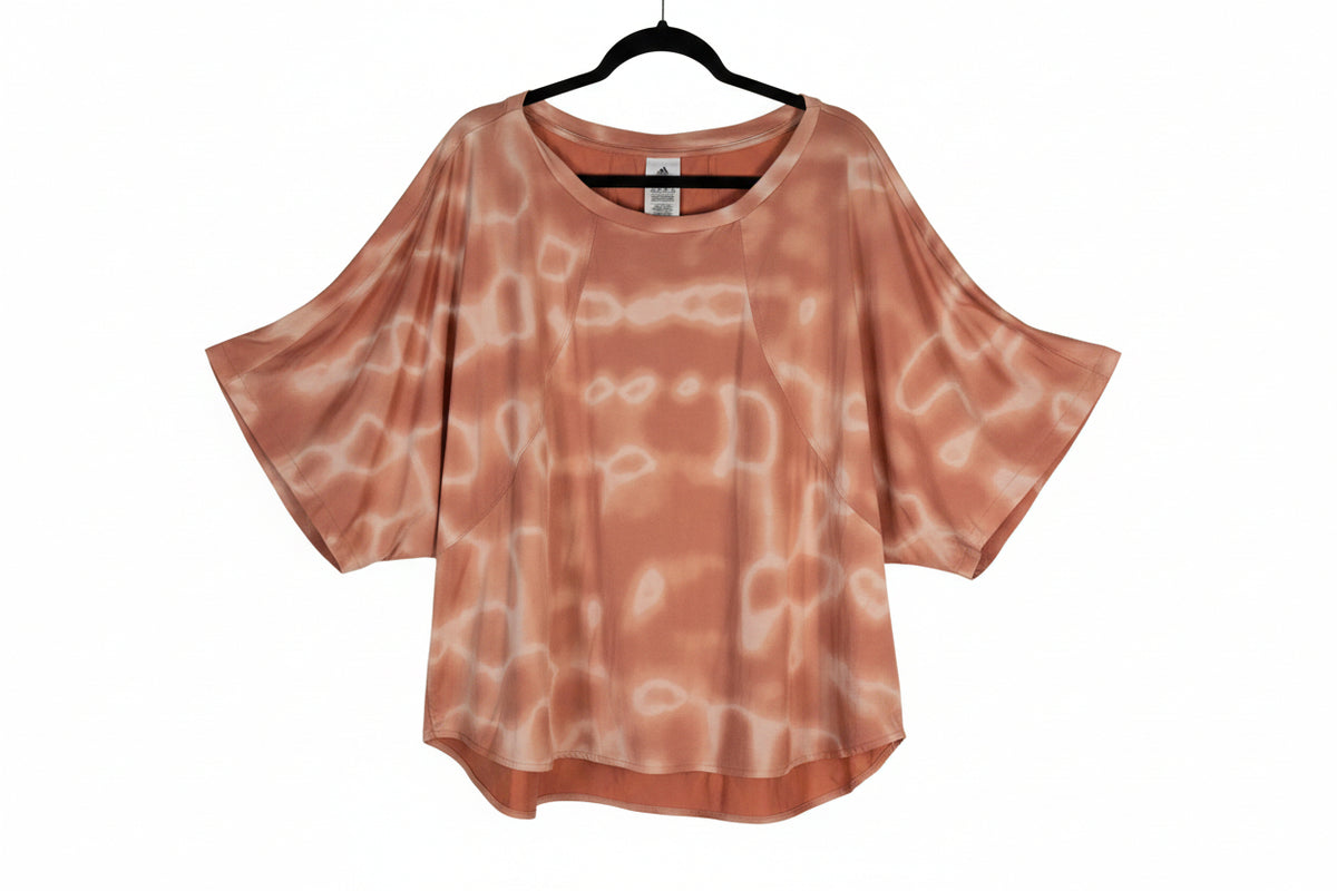 Adidas 11 HONORE' 2X loose, short-sleeve top in a peachy orange color with a white tie-dye pattern.