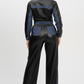 A model viewed from the back wearing a black and blue two-tone 2-piece set with a faux-leather finish and denim-like side panels.